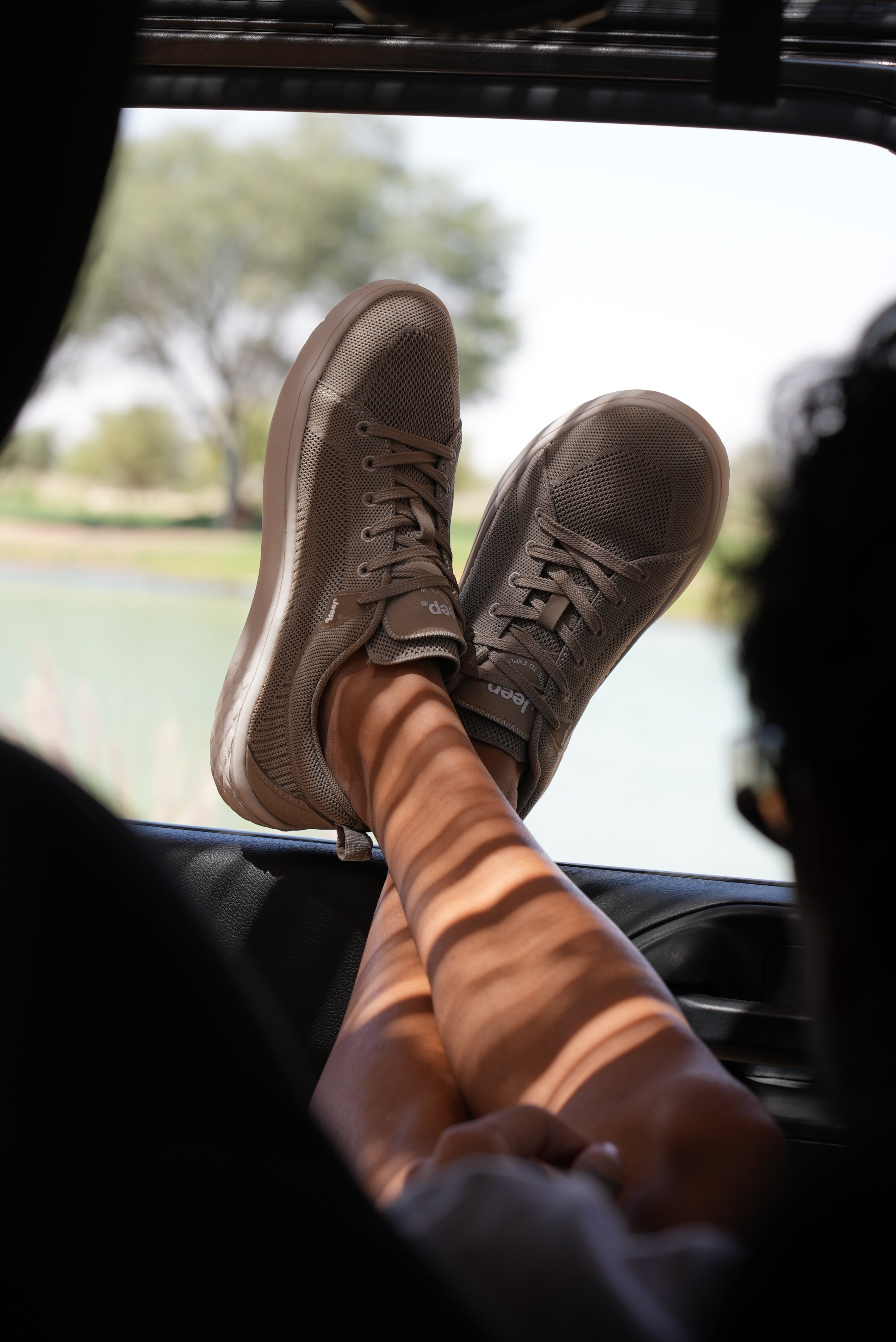 Man wearing Jeep beige shoes sitting inside a Jeep