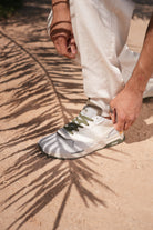 Man wearing a off-white Jeep sneaker with green accents on a sandy surface